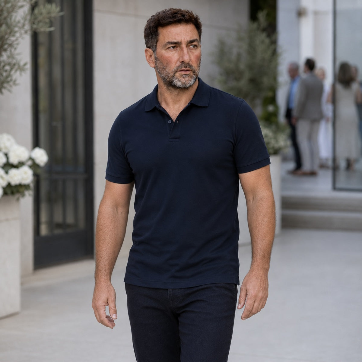 Homme en polo bleu marine marchant devant une entrée claire