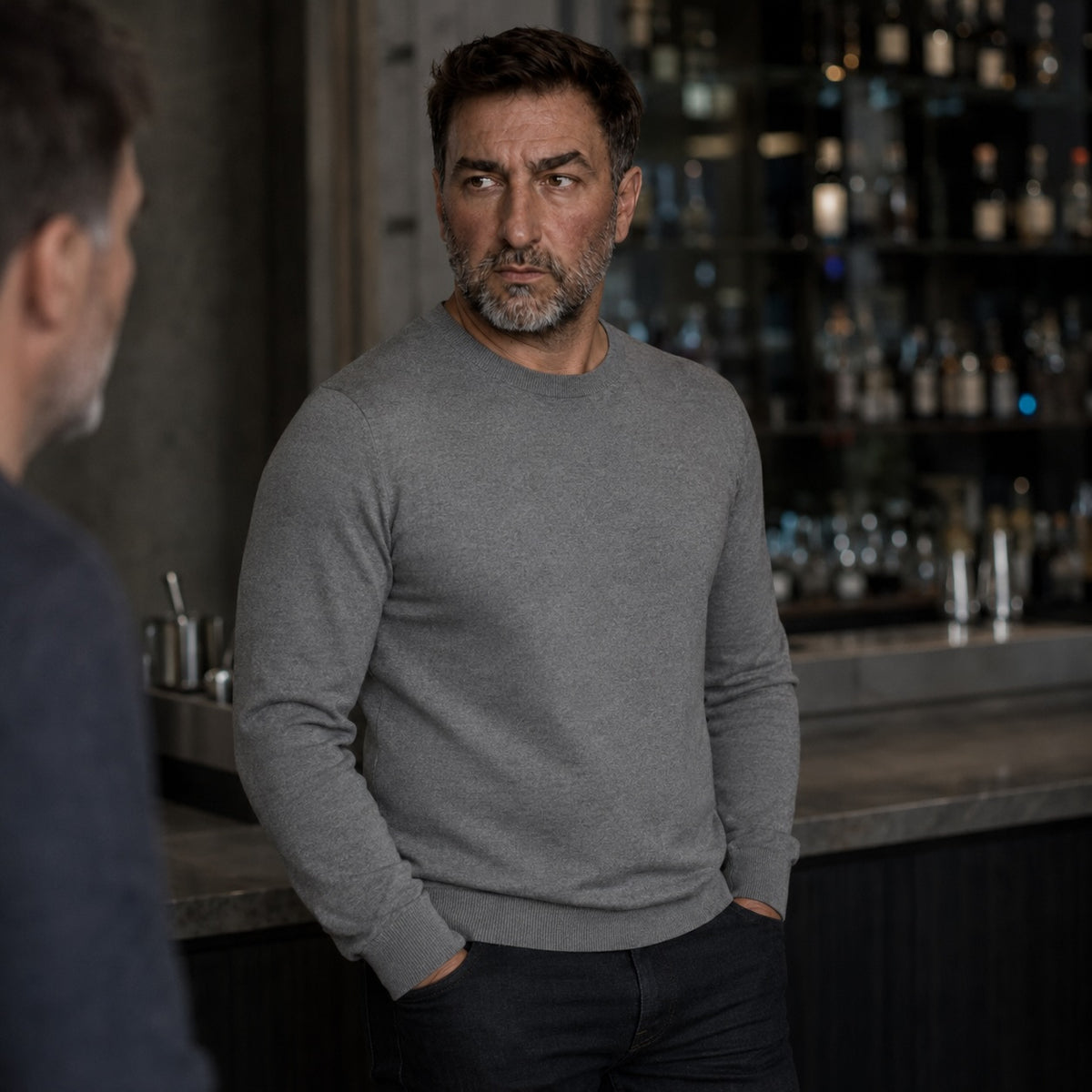 Homme en pull fin gris debout à un comptoir de bar